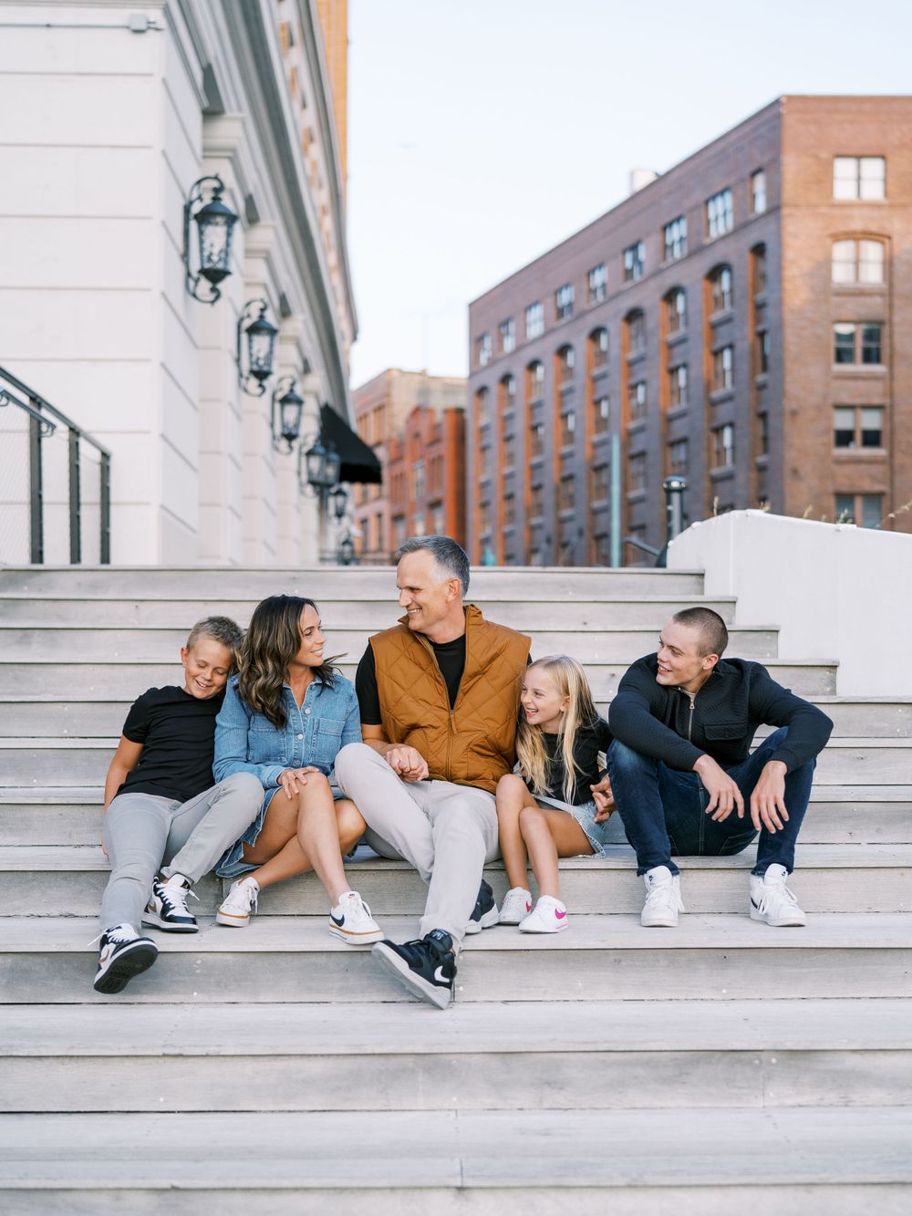 People lounging casually on white stone steps against a brick building backdrop.