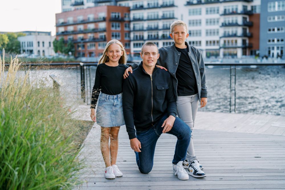 Family walking together on wooden boardwalk near waterfront apartments.