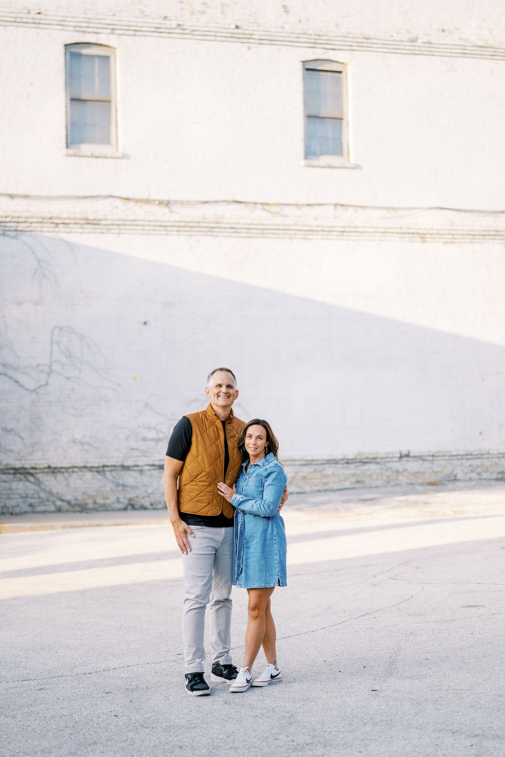 Casual outdoor portrait session against a minimalist white wall background.