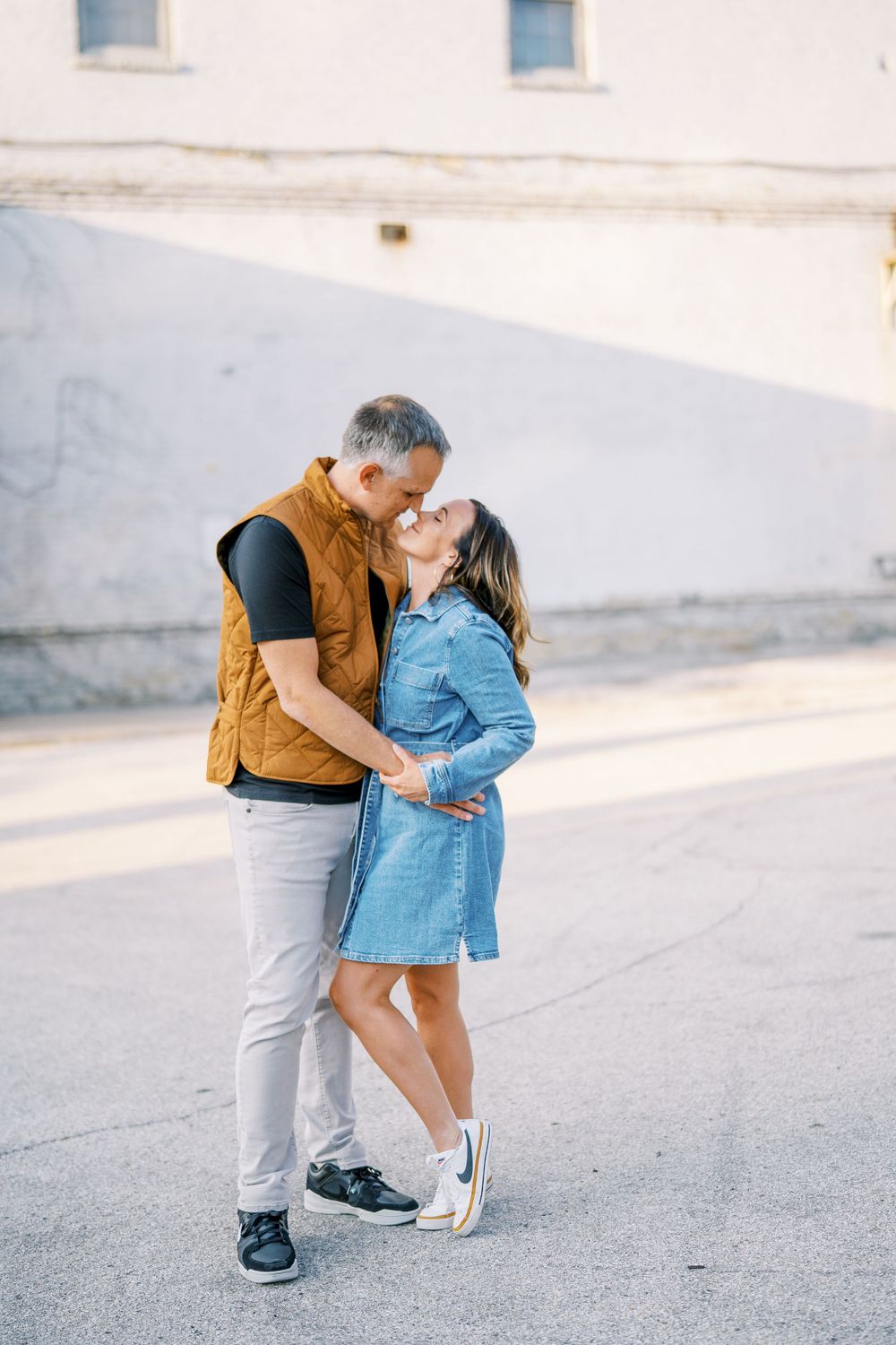 Sweet candid moment captured against a white wall during an outdoor photoshoot.