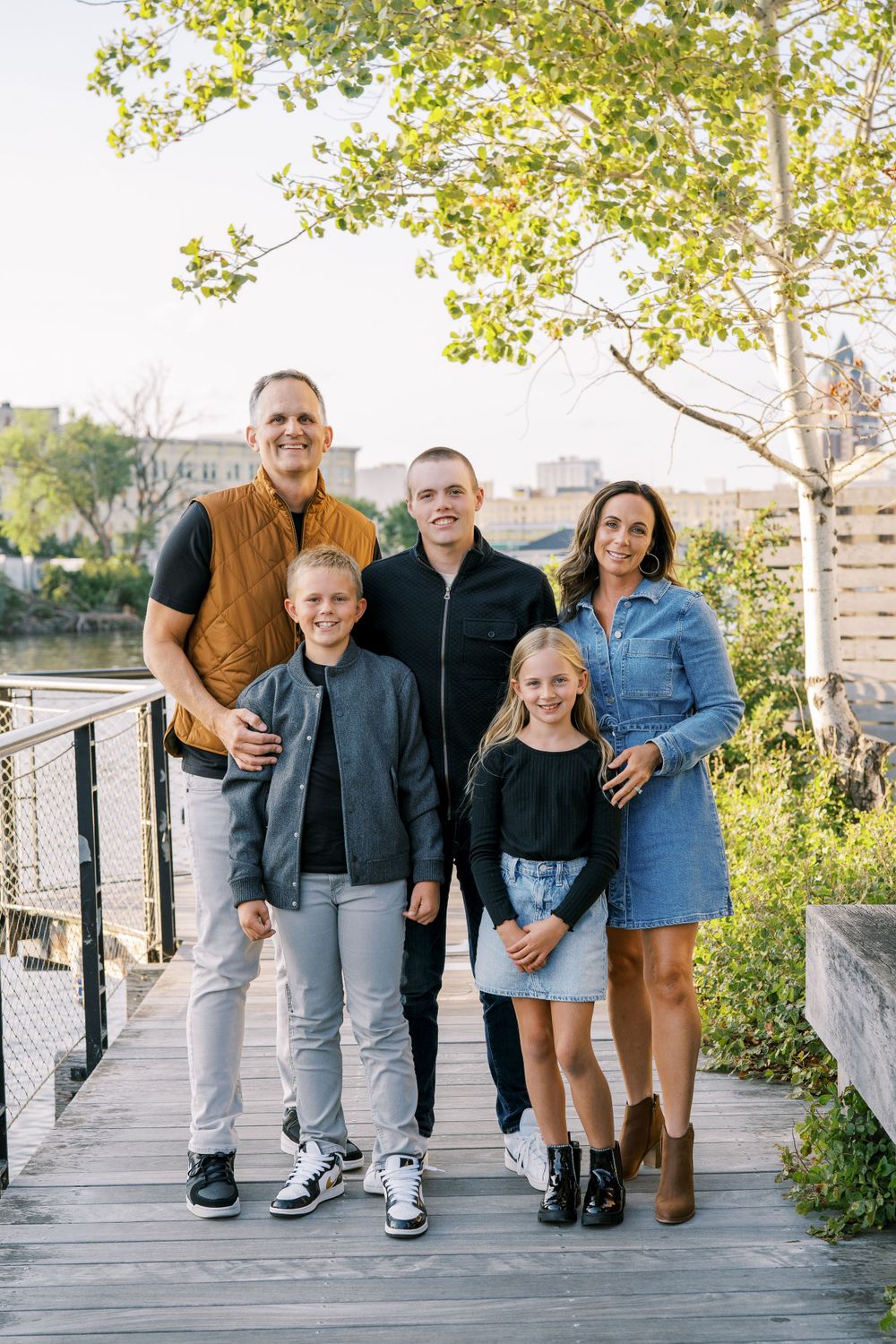 Family group portrait on wooden deck with city buildings visible in background.