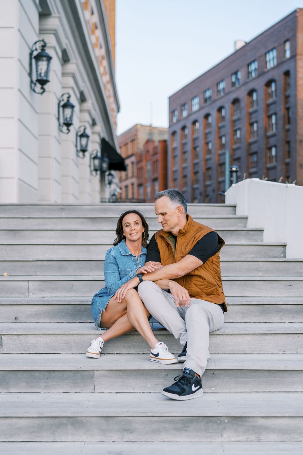 Two people relaxing on concrete steps with a brick building in the background.