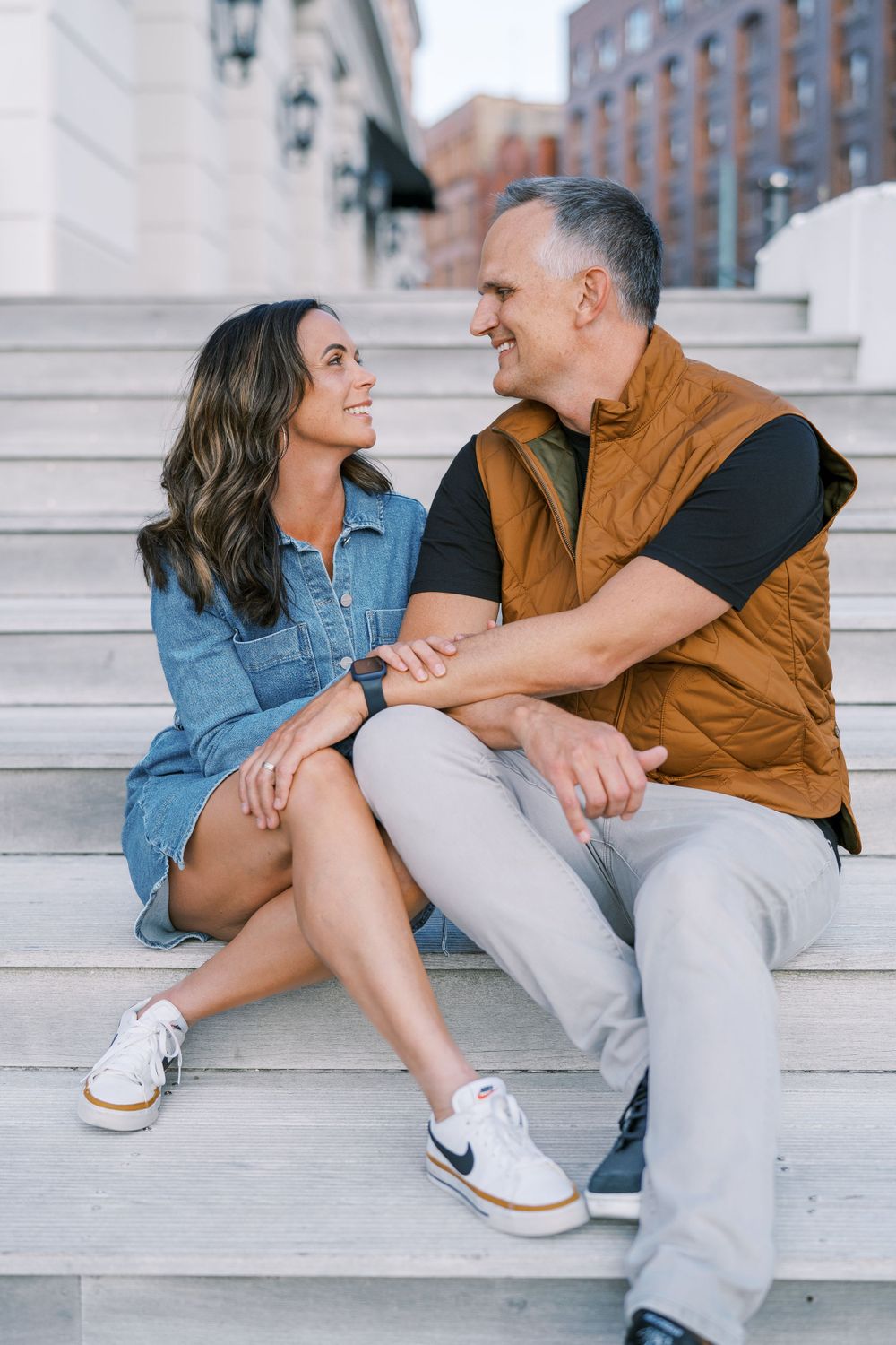 Two people sitting close together on outdoor stone steps in an urban setting.