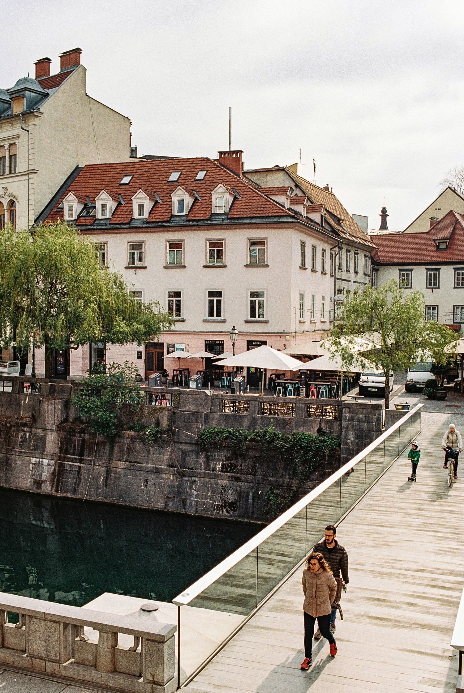 Riverside buildings with traditional architecture and modern walkway along Ljubljana's canal.
