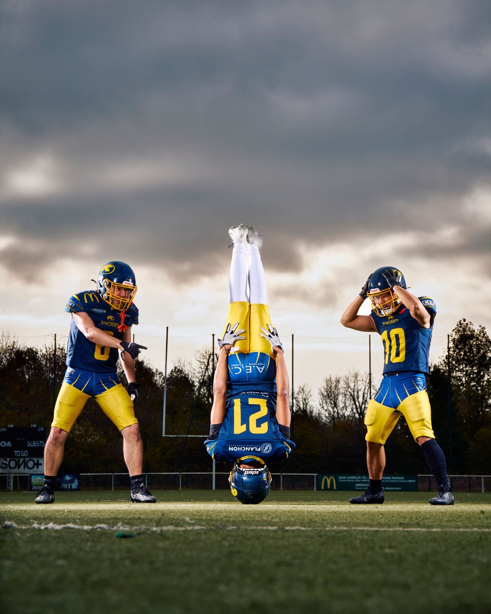 Des joueurs de football créent une photo d'équipe créative en posant la tête en bas dans le ciel du coucher de soleil.