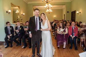 Smiling bride and groom walk down the aisle together after their wedding ceremony.