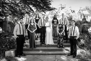 Wedding party poses together in black and white photo outside a grand manor house.