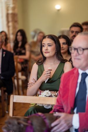 Emotional bridesmaid in green dress watches wedding ceremony while seated among guests.