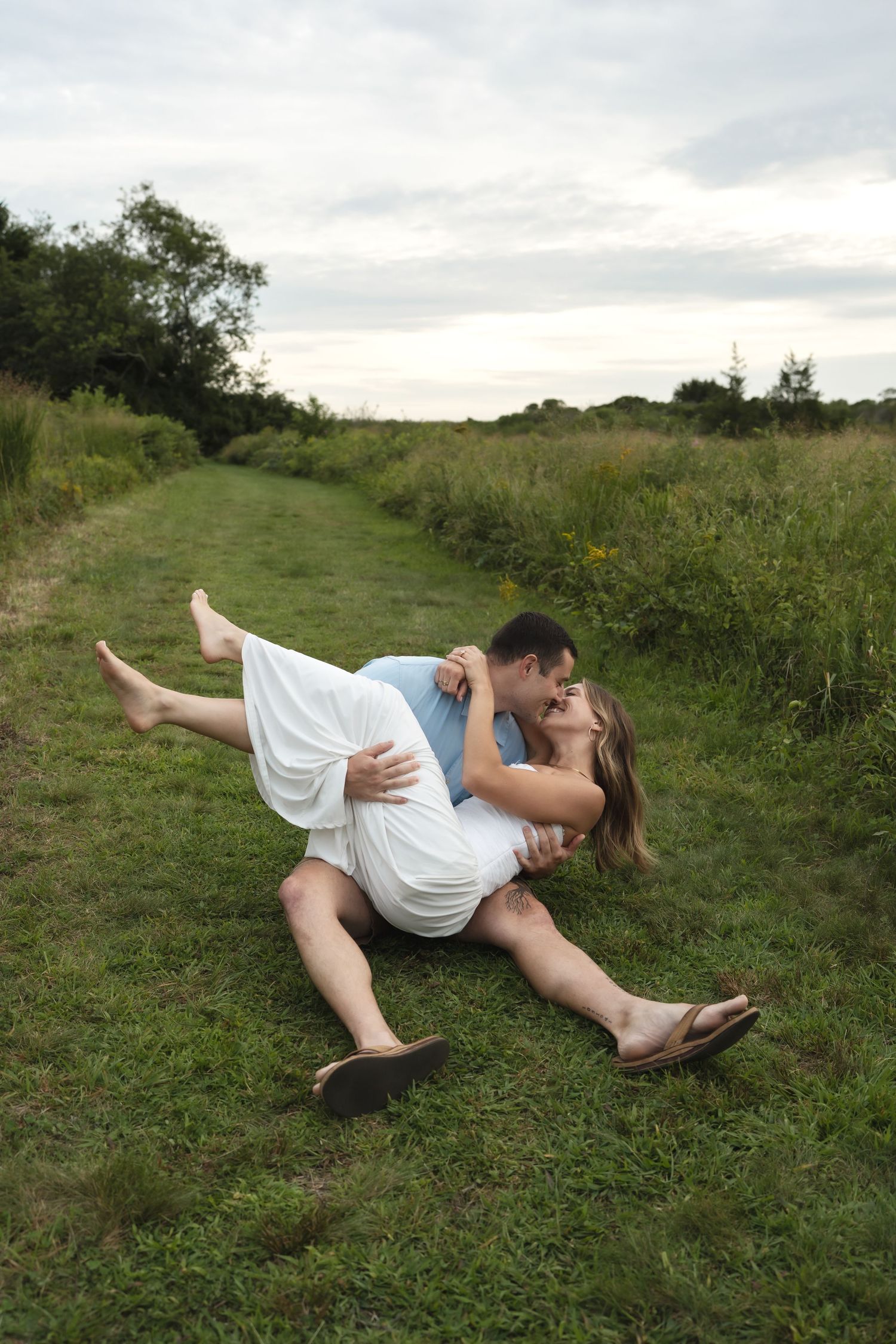 A couple stands in a green field flying paper airplanes, woman in white dress, Candlelight Farms located in Connecticut
