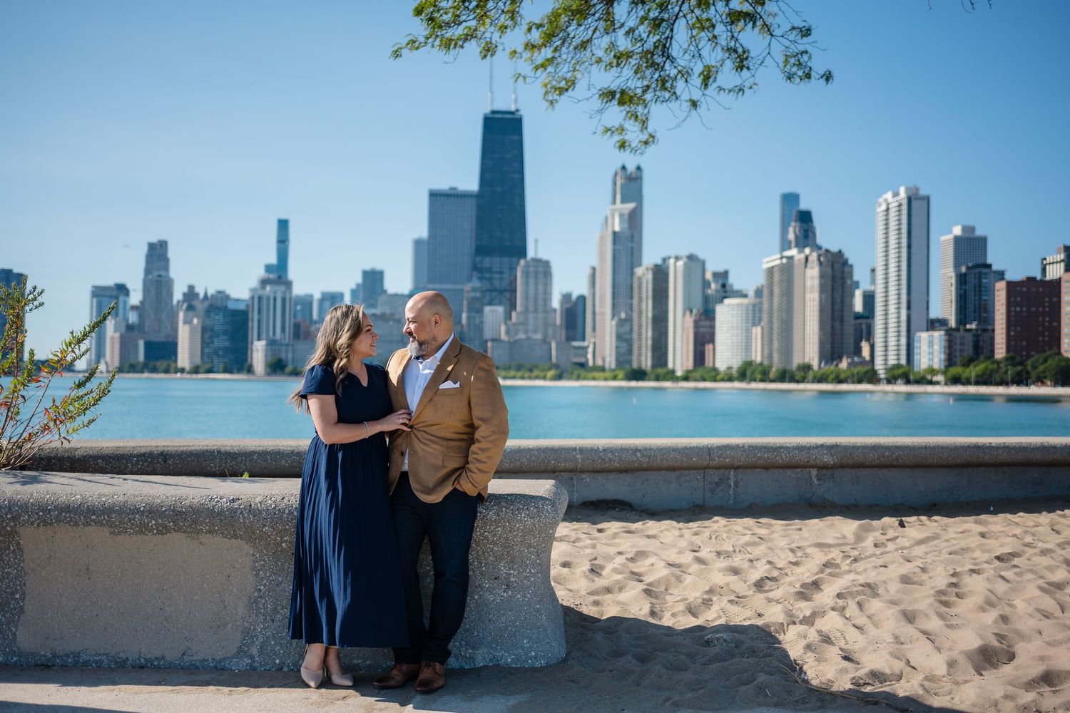 Couple poses by Lake Michigan with Chicago skyline backdrop on a sunny day.
