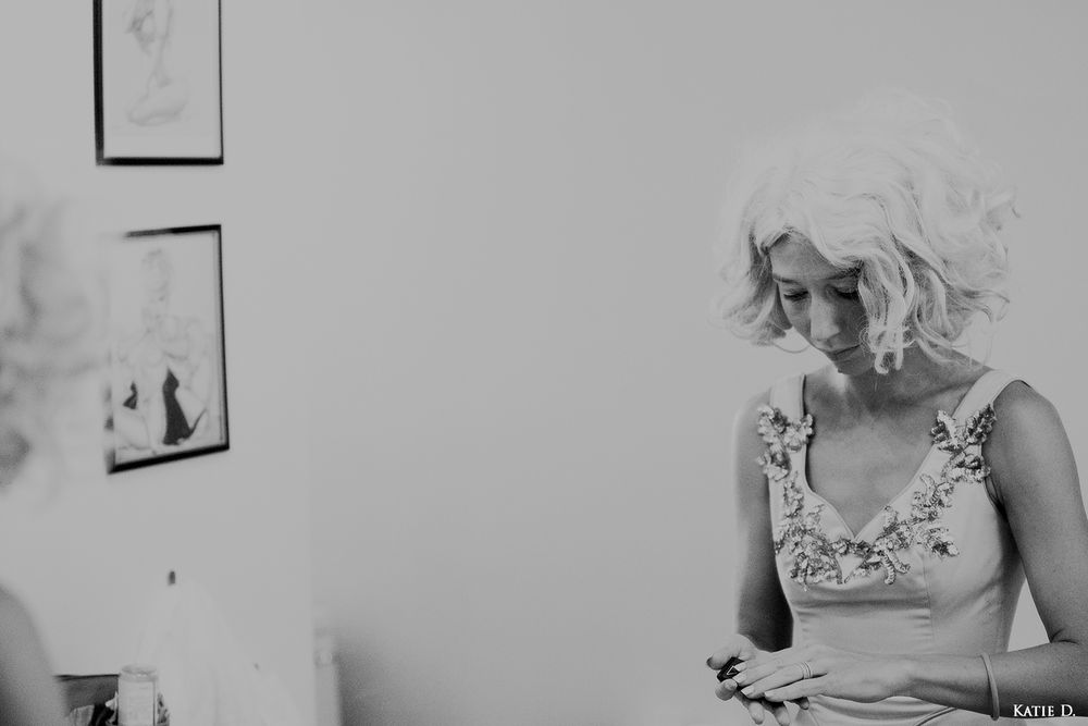 Black and white portrait of blonde woman in embroidered dress looking down thoughtfully indoors.