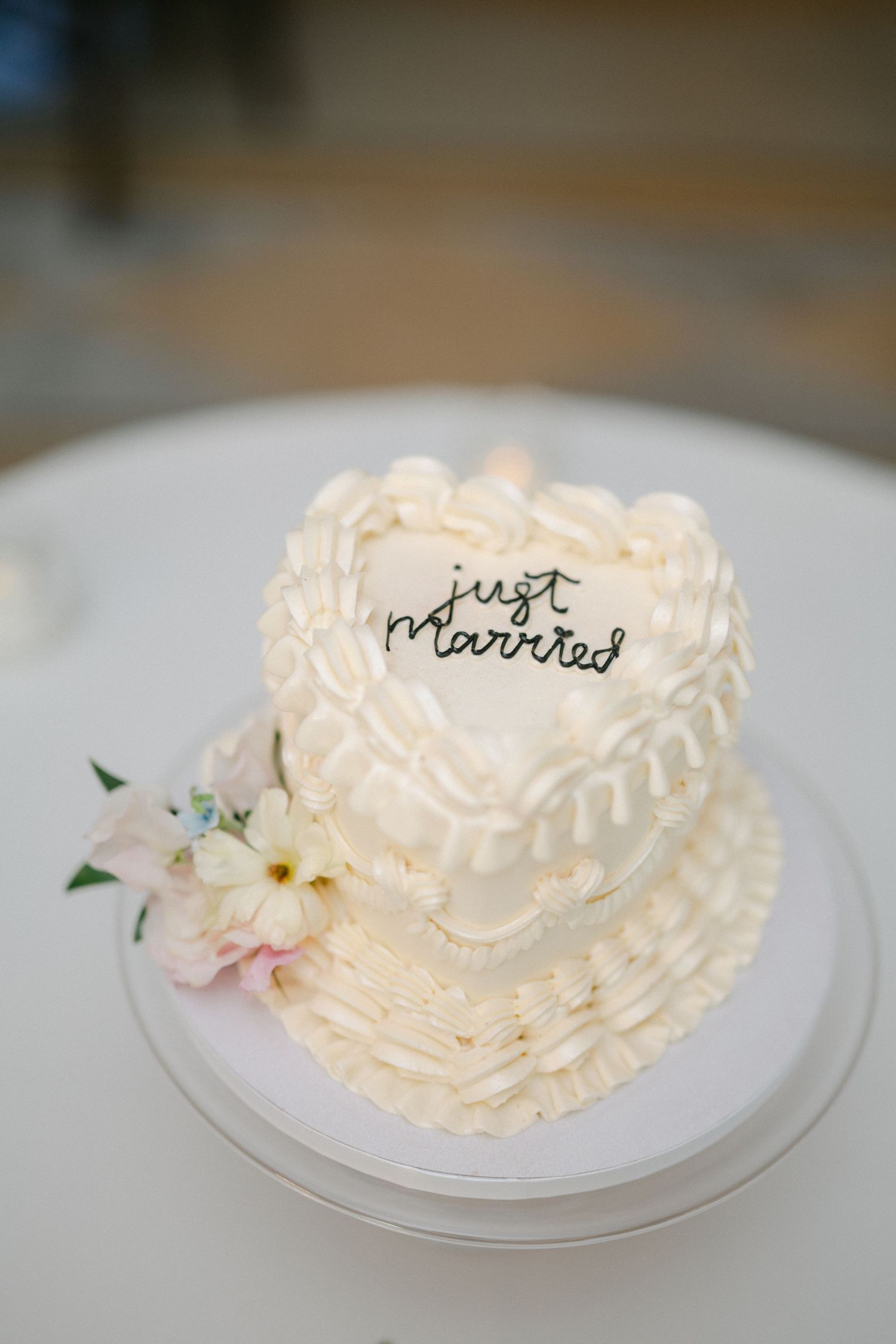 Black and white photo of a bride in lace gown raising her arm at wedding reception table with elegant place settings.