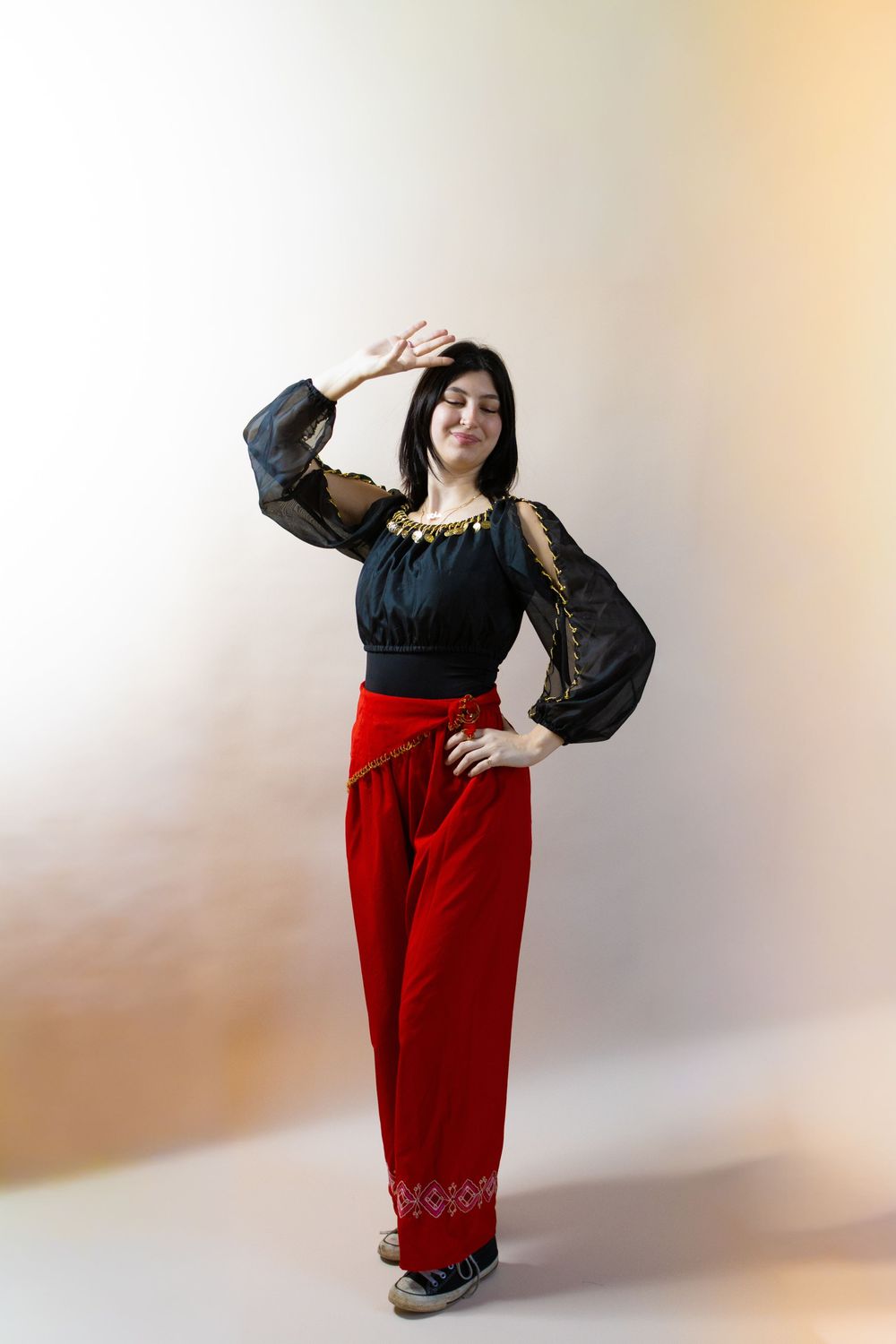 Woman in traditional costume strikes playful poses against white studio backdrop.