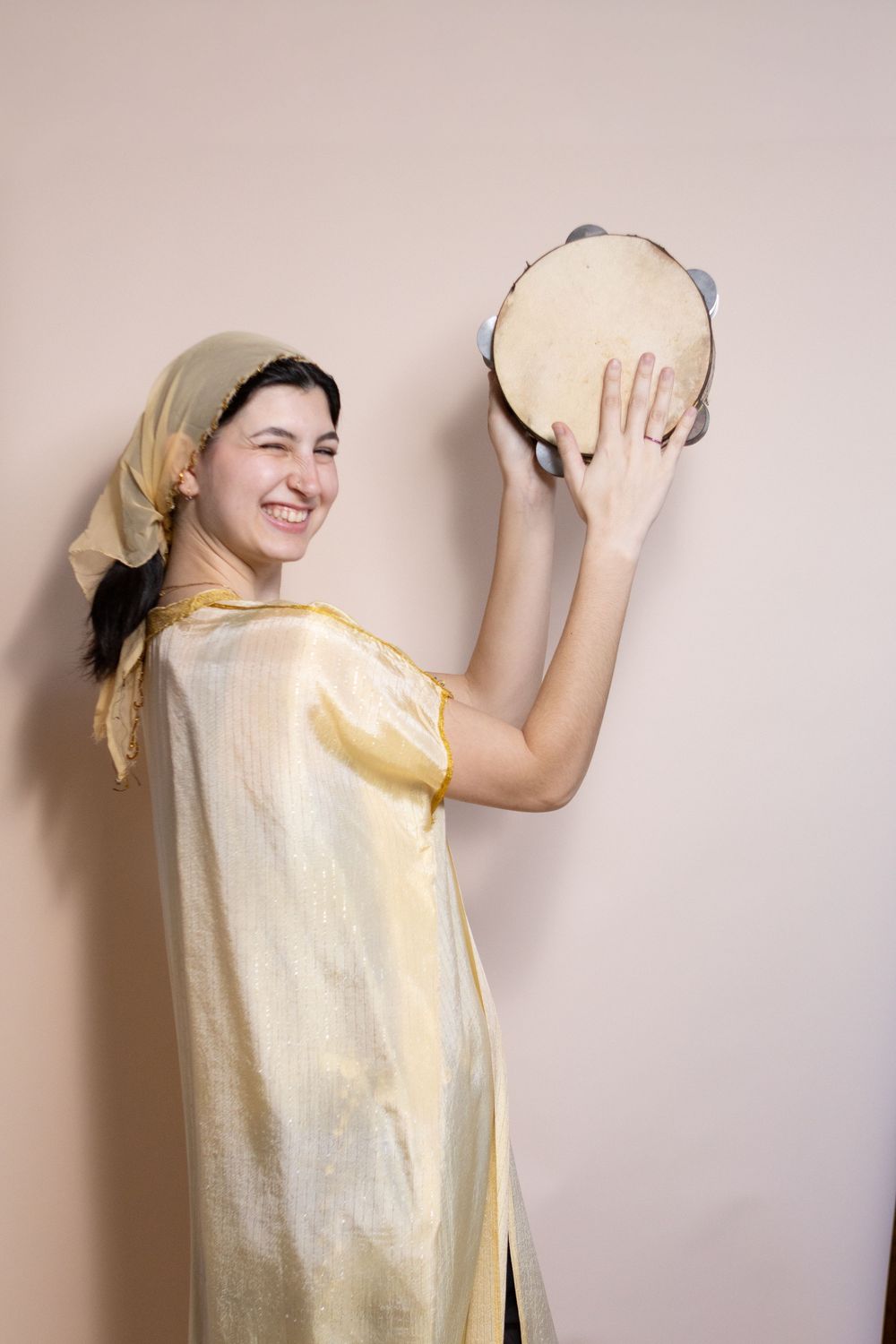 Person in light yellow outfit poses playfully against neutral background.