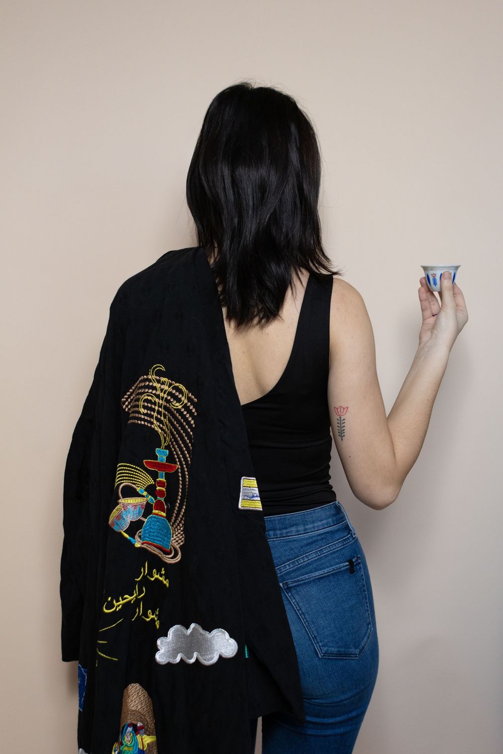 Person in black t-shirt with colorful graphic design writing on a wall.