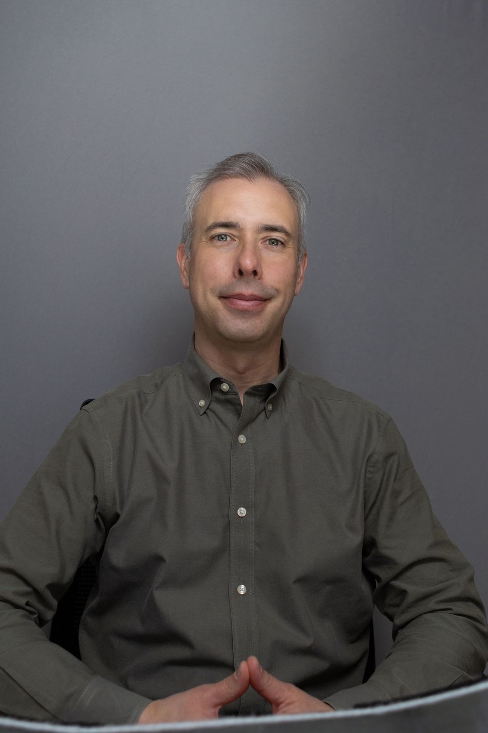 Series of professional headshots of person in olive button-down shirt against grey background.