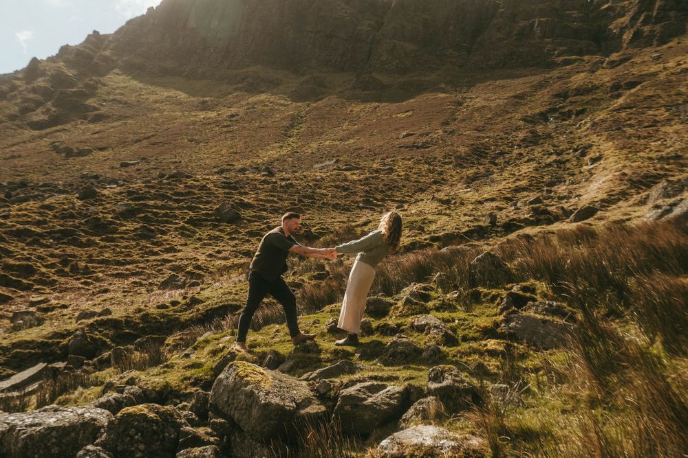 landscape image of a couple dancing in rugged Irish wilderness holding hands, while she is leaning back