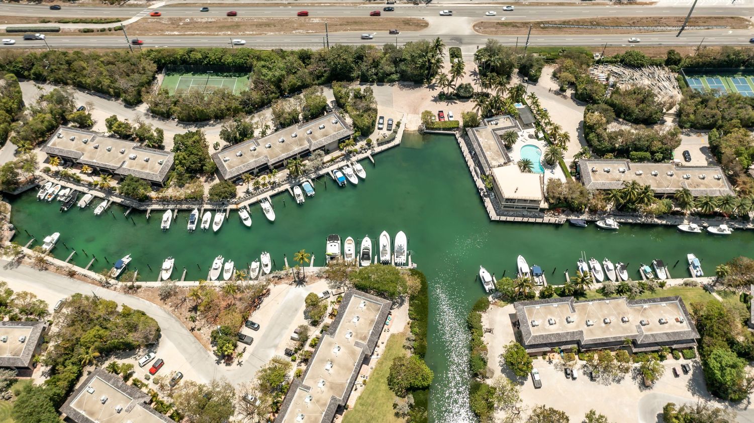 Aerial view of a luxury waterfront marina community with boats docked along green canals surrounded by condos.