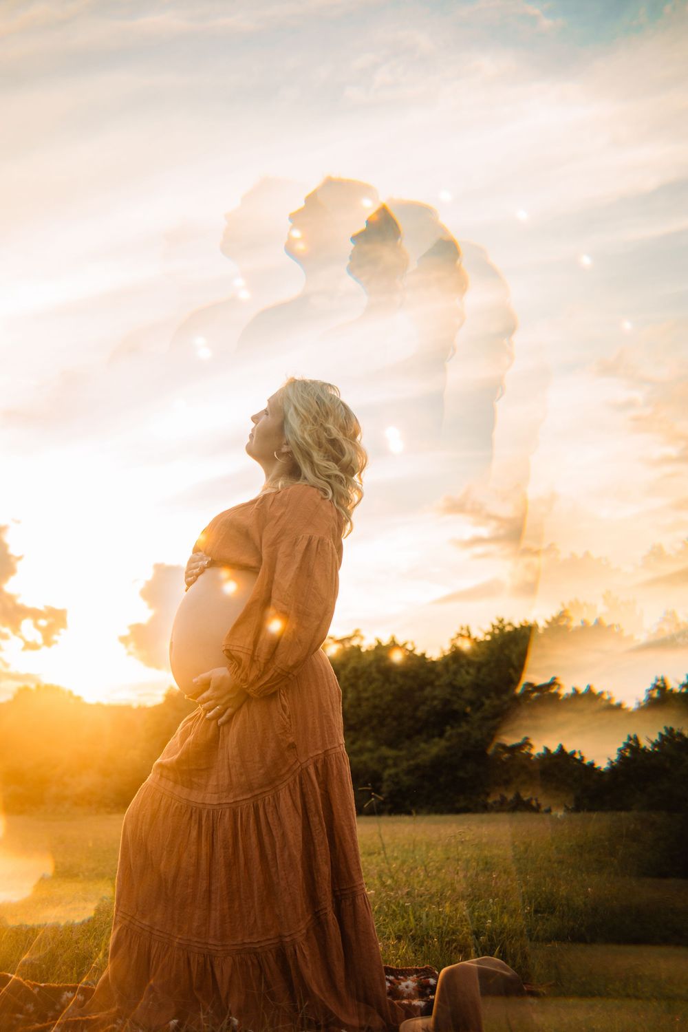 Double exposure of pregnant woman in rust dress cradling belly with couple silhouette at golden sunset.