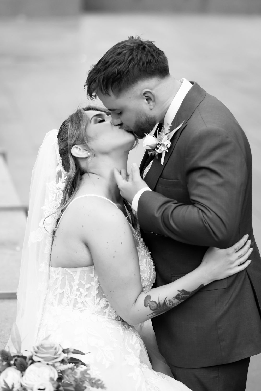 Black and white photo of a bride and groom sharing a romantic kiss on their wedding day.