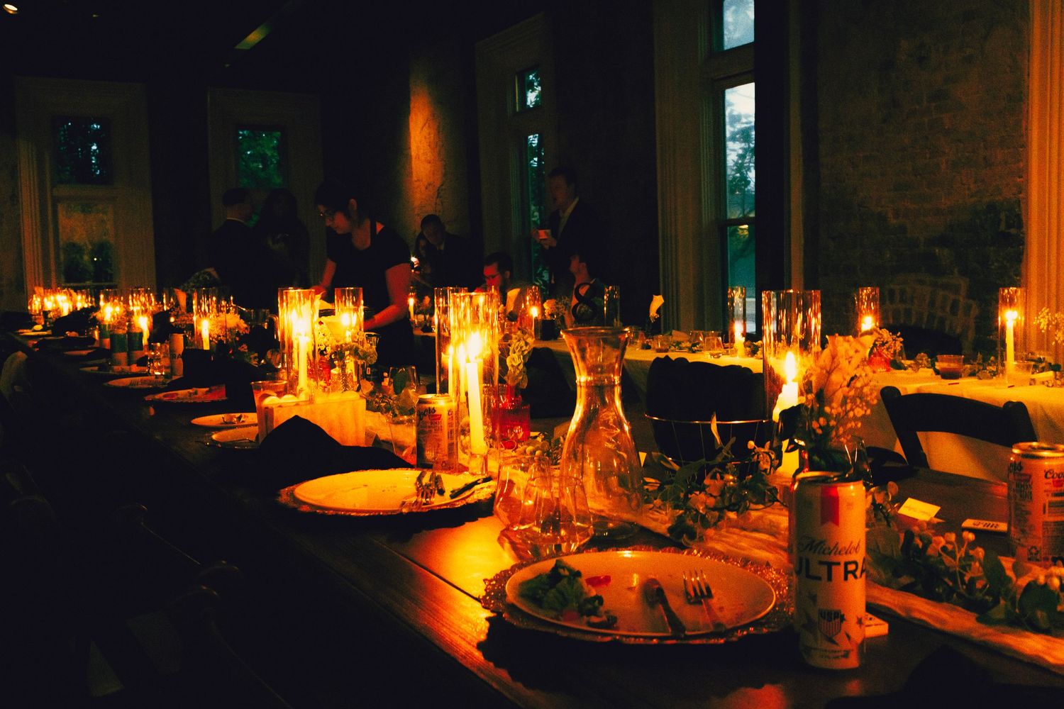 Elegant candlelit dinner table set for a formal event in a dimly lit restaurant with glowing candles and place settings.