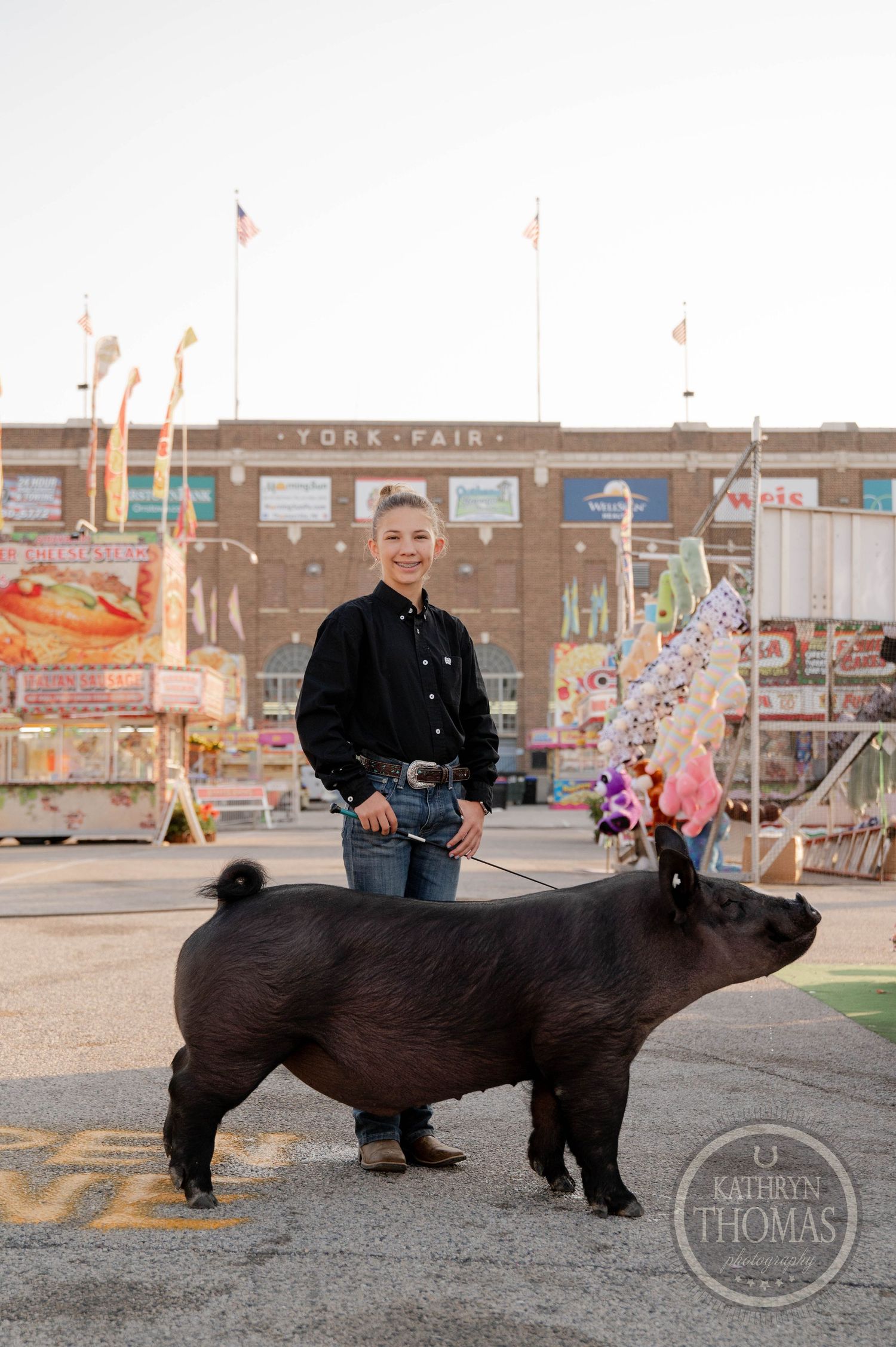 Youth exhibitor proudly stands with black show pig at York Fair livestock competition.