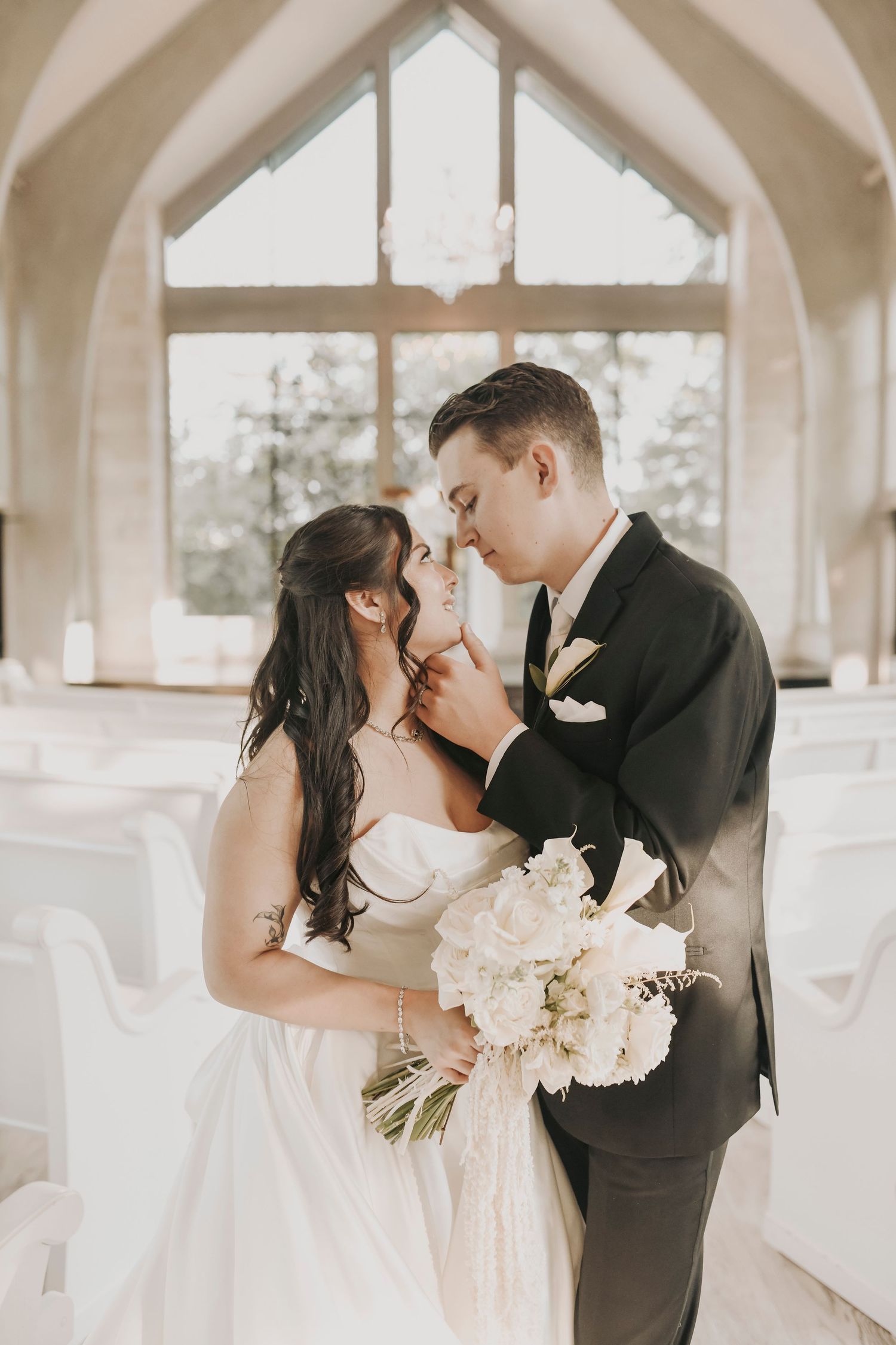 Bride and groom standing beneath floor-to-ceiling windows