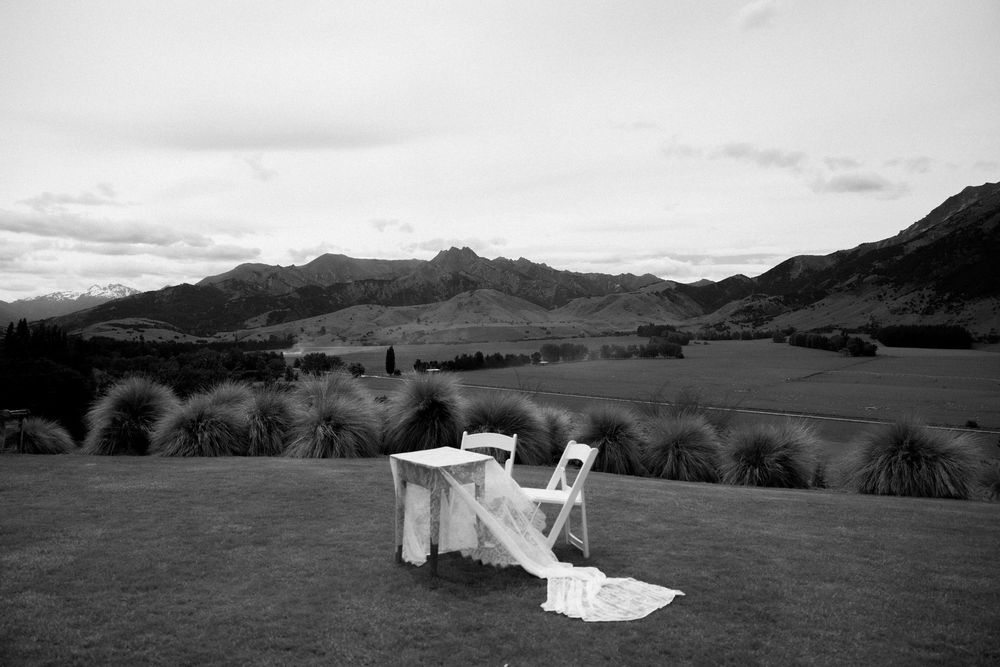 Black and white wedding table setup on lush lawn with stunning mountain and valley backdrop in New Zealand.