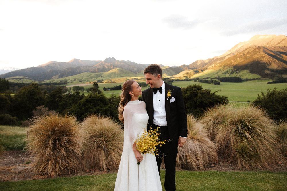 Bride and groom share a romantic moment with stunning mountain valley backdrop at golden hour.