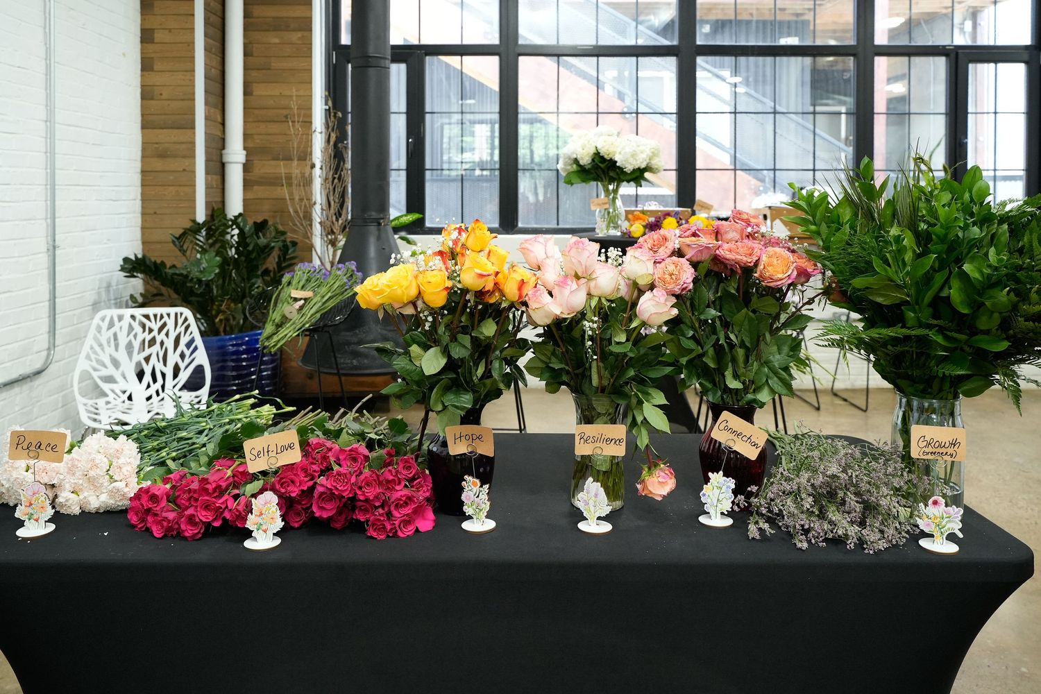 Colorful flower bouquets displayed on a black tablecloth with small decorative figurines at an indoor floral market.