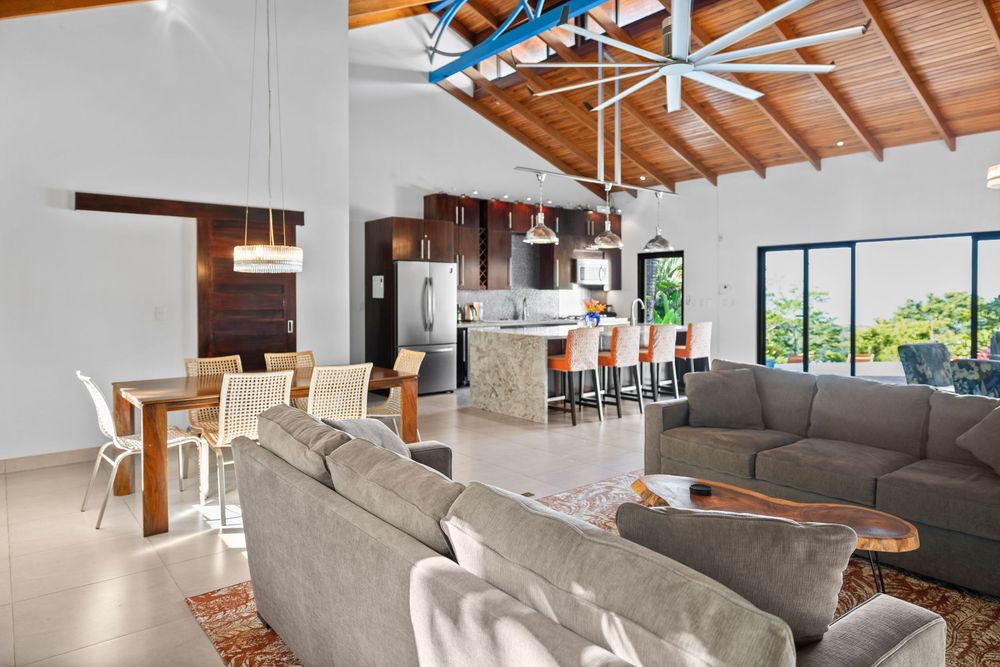 Spacious open-plan living area with vaulted wood ceiling, large ceiling fan, and modern kitchen.
