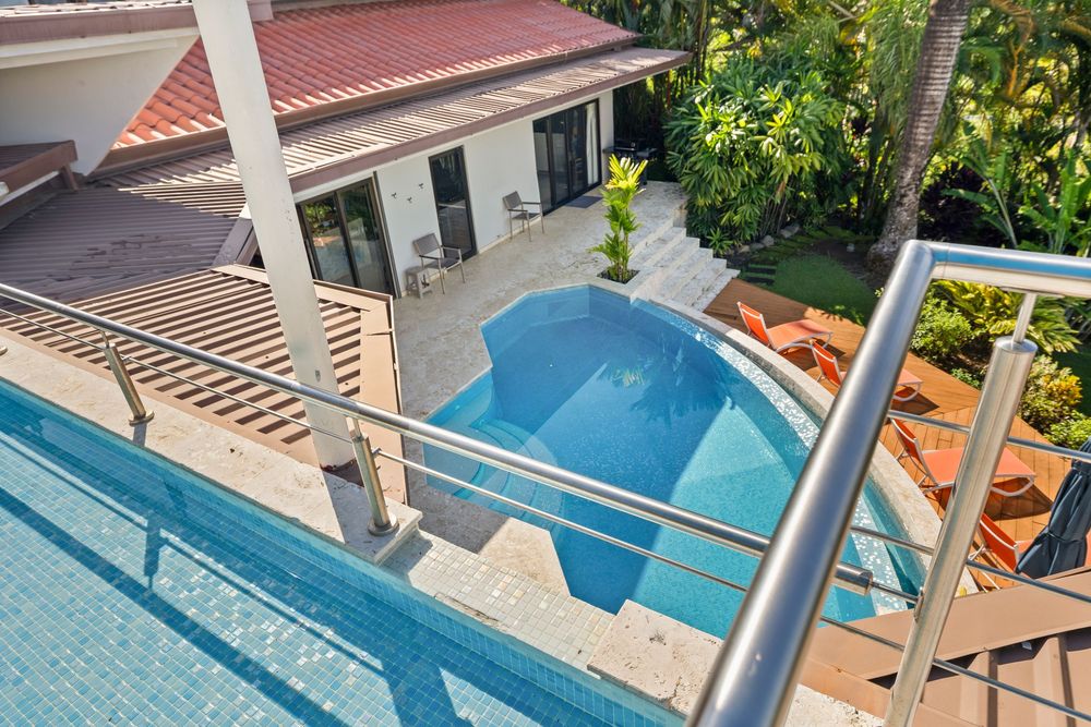 Aerial view of a luxury villa with a sparkling blue pool surrounded by lush tropical landscaping.