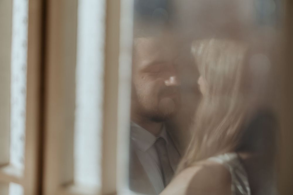 Romantic blurred wedding couple almost kissing, captured through frosted glass window.