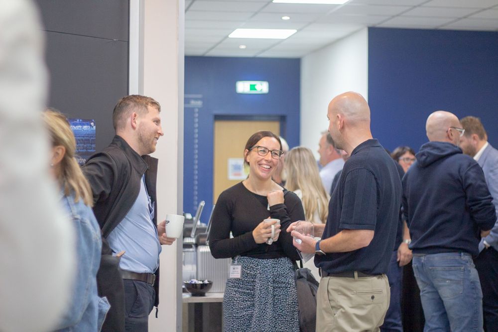 Professionals networking and socializing with drinks at an indoor business event.
