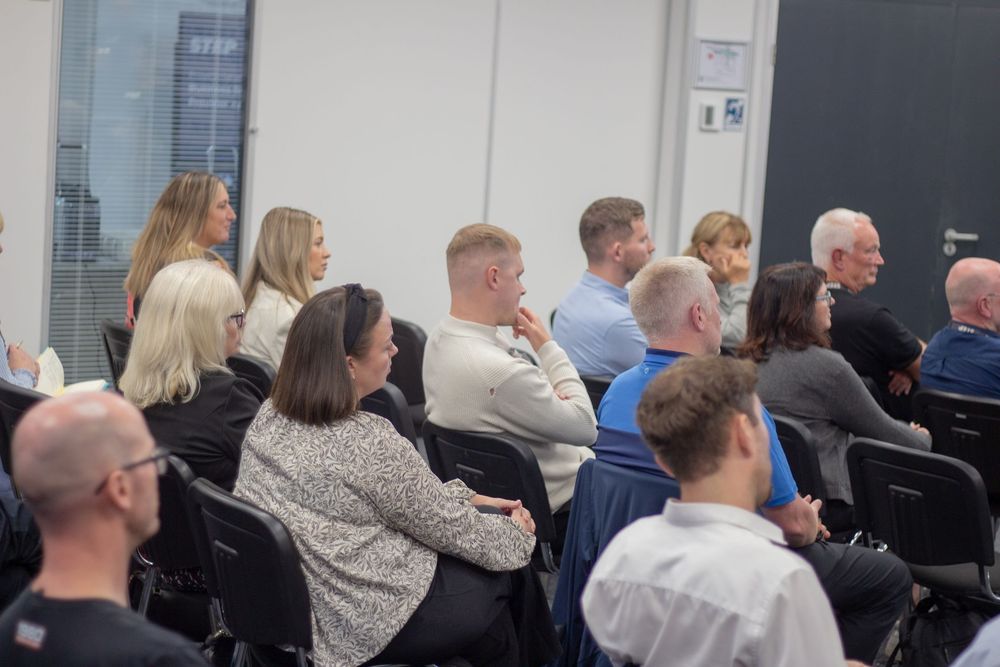 Diverse group of professionals seated and attentively watching a presentation at a business event.