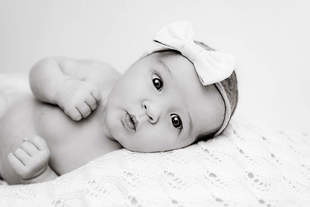 Close-up black and white portrait of a newborn baby girl with wide eyes by Lake Elsinore family and newborn photographer.