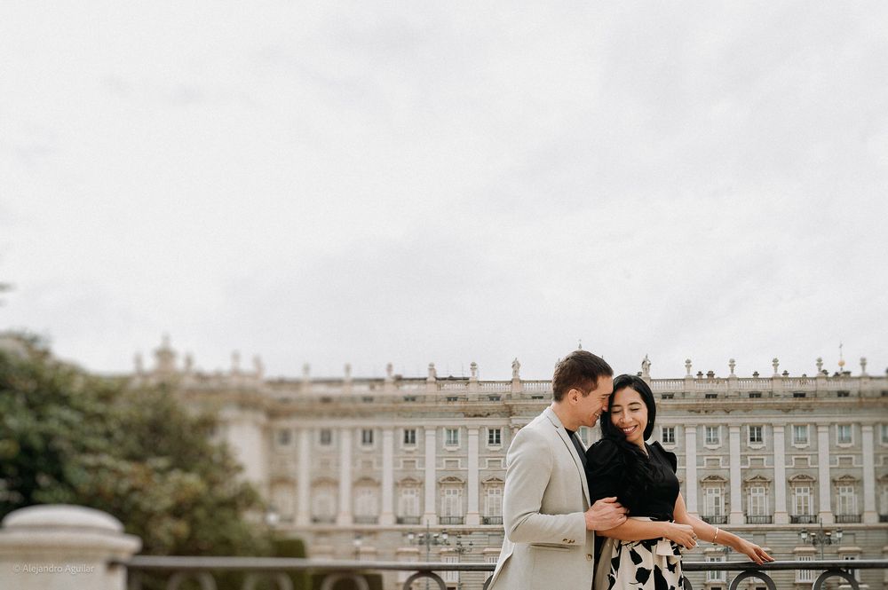 Romantic couple embracing near the Royal Palace of Madrid on a cloudy day.