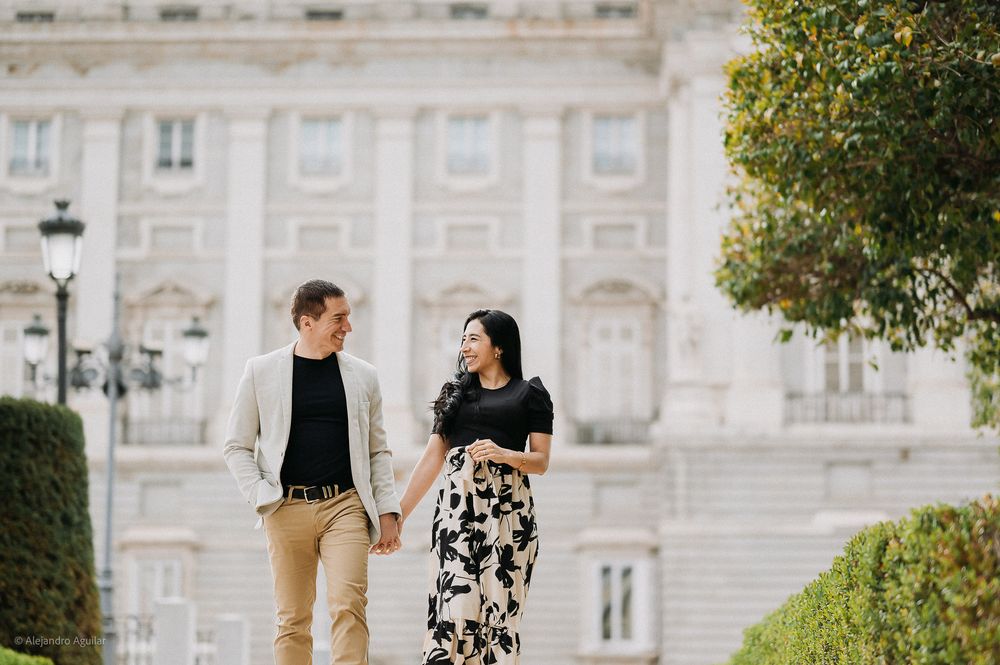 Happy couple walking hand in hand through the gardens of Madrid Royal Palace.