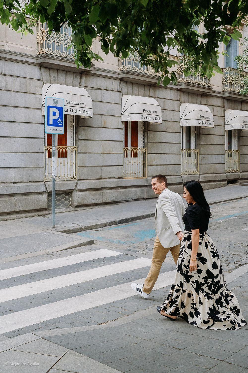 Stylish couple crossing a zebra crossing on a classic Madrid city street.