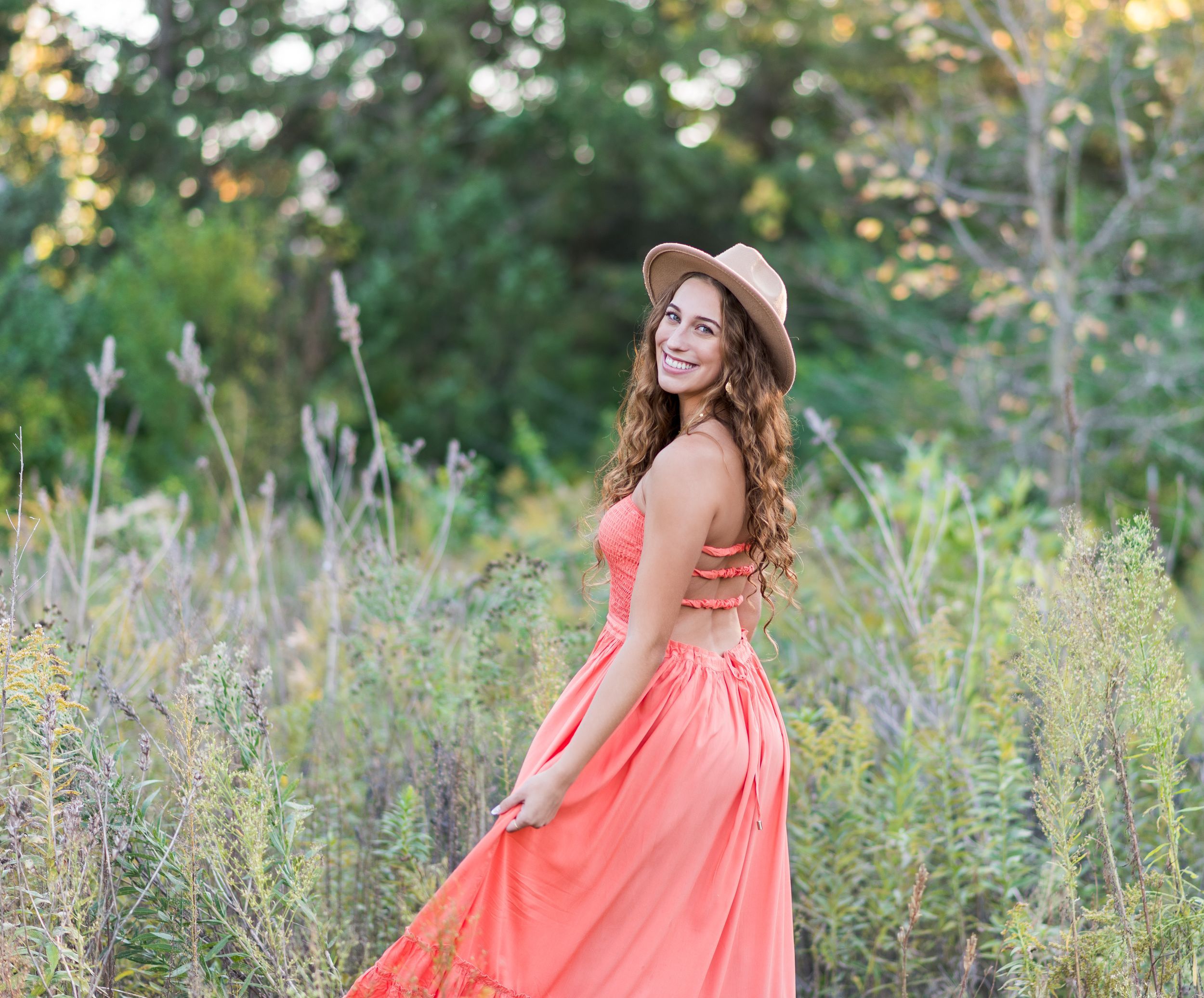 Central Illinois high school senior posing outdoors in a coral dress during a golden hour senior photo session.