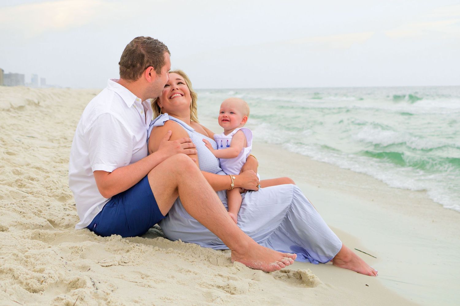 A relaxed family moment captured on a sunny beach with waves in the background.