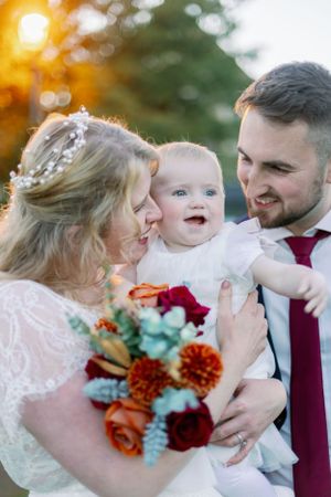 A tender family moment at a wedding with autumn-colored flowers and golden bokeh lighting.