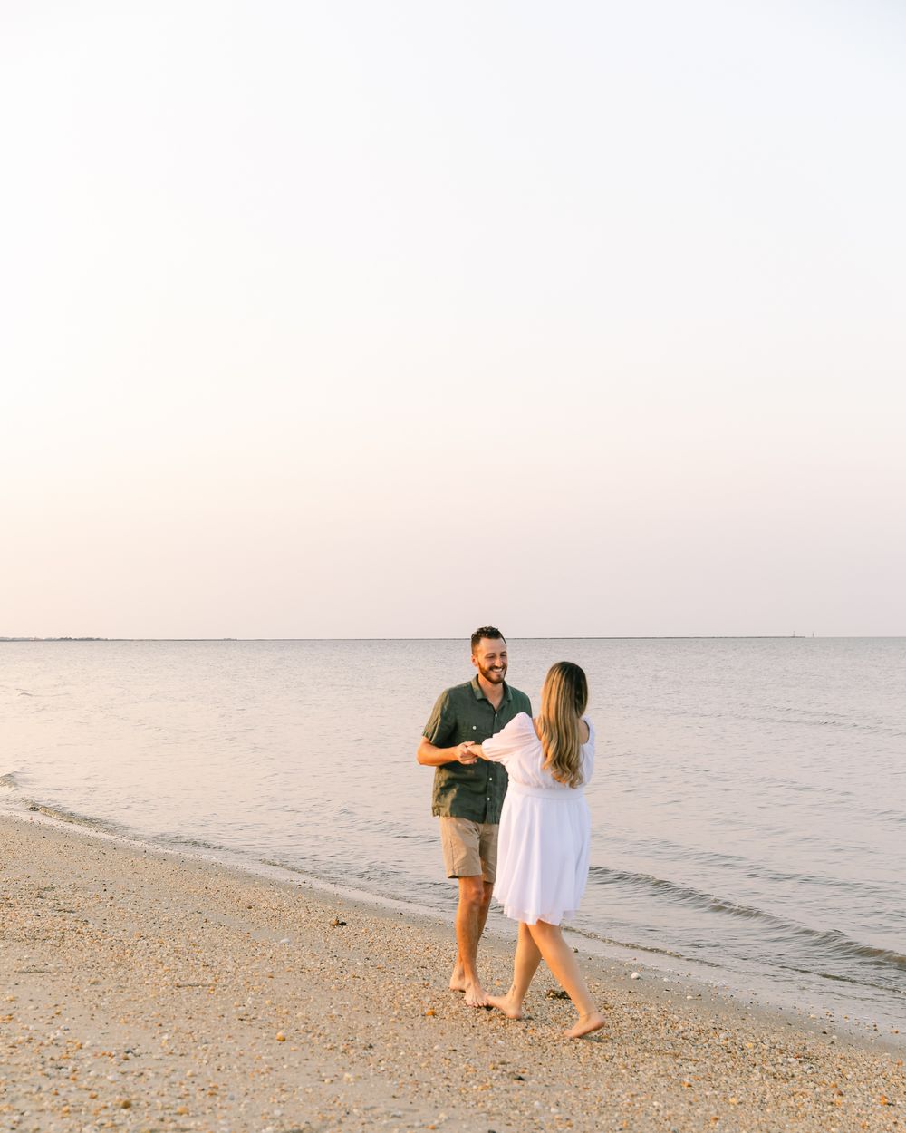 A couple takes a romantic stroll along a serene beach at sunset.