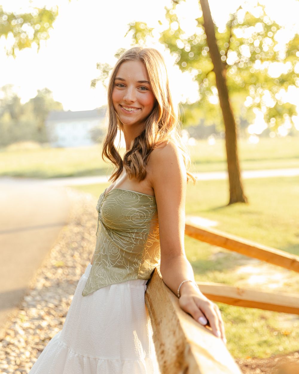 A person in a white dress poses in golden sunlight during sunset.