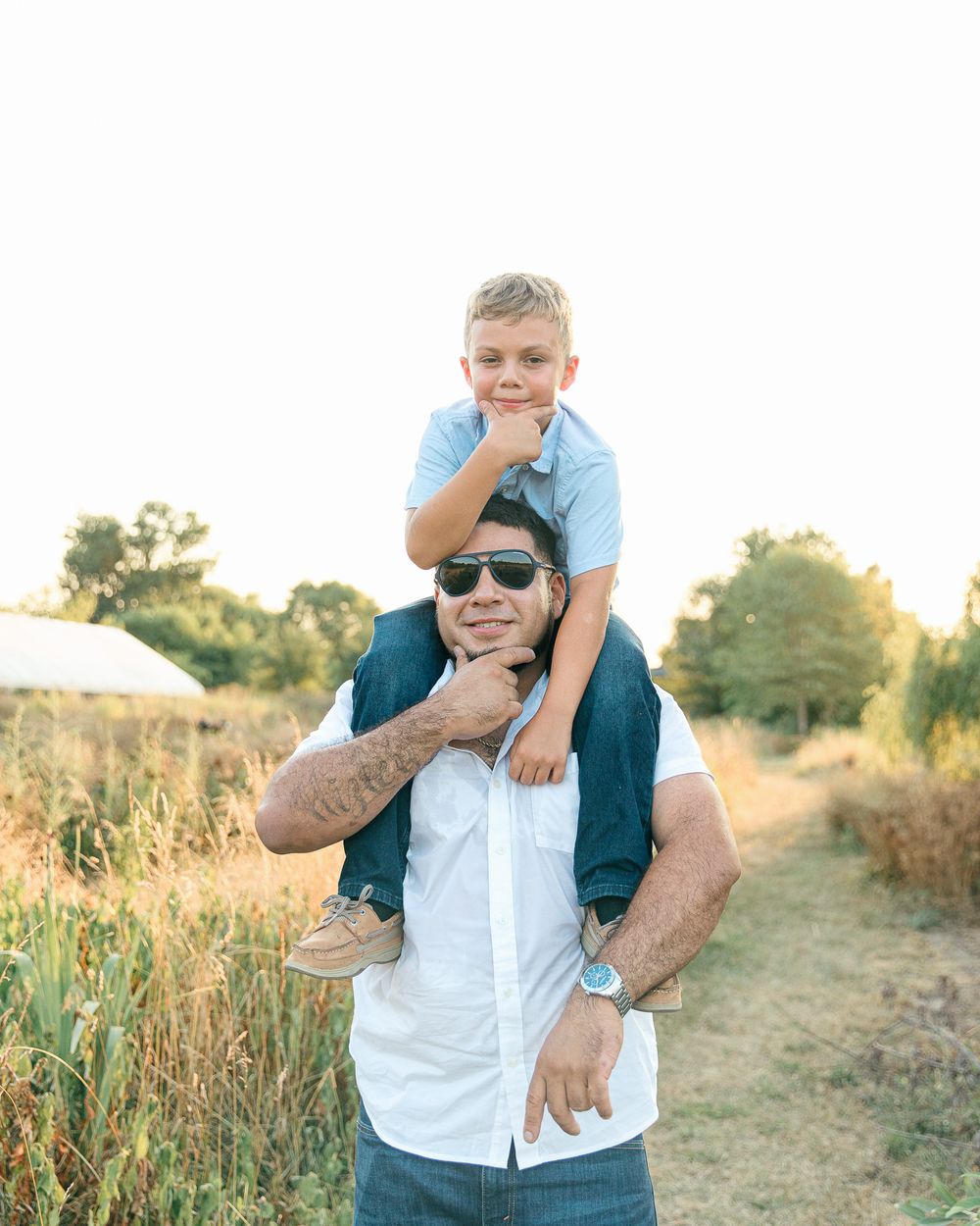 A father and son enjoy a playful moment outdoors at sunset on a rural path.