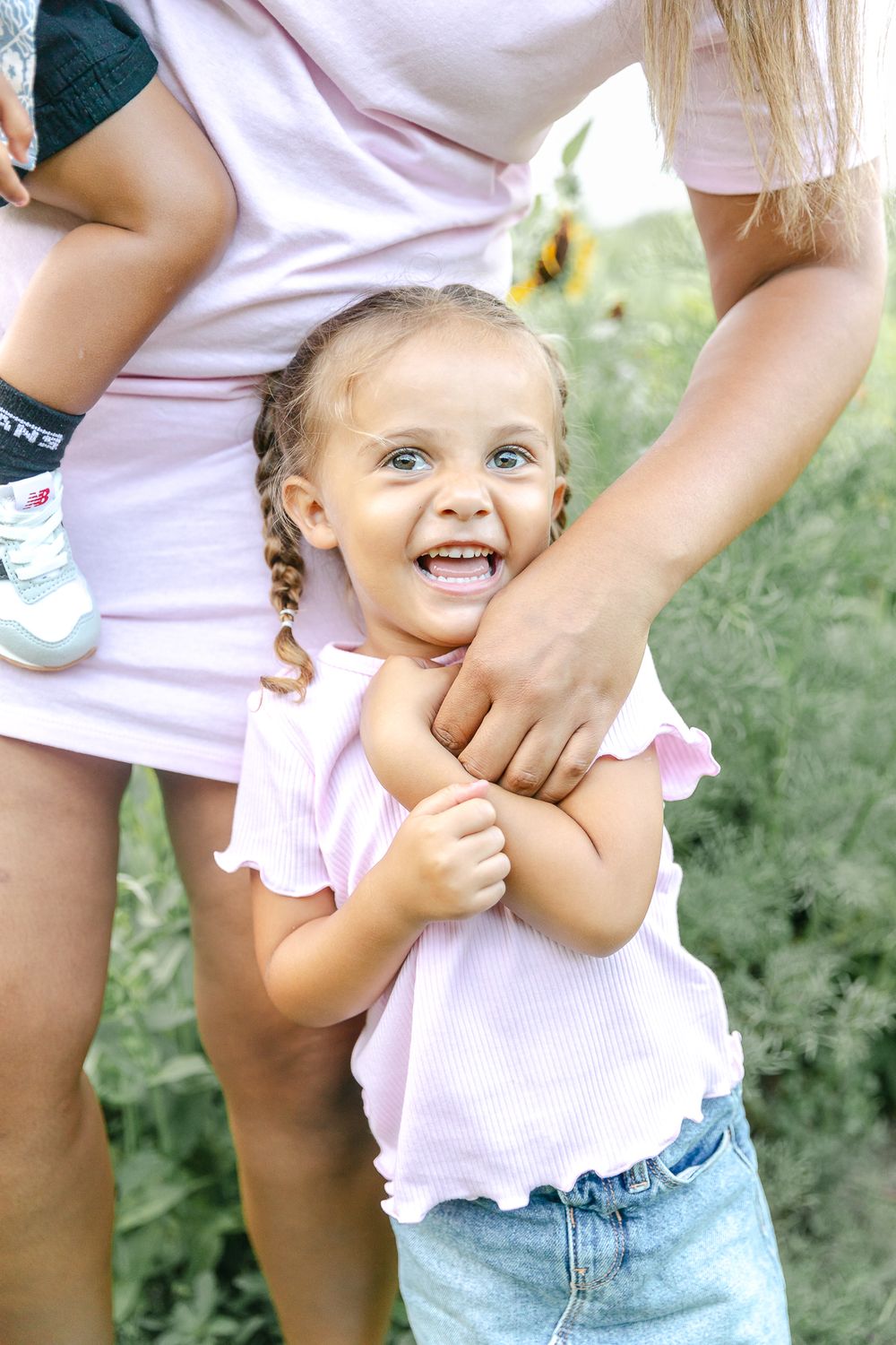 A child in pink clothing laughs while playing outdoors.