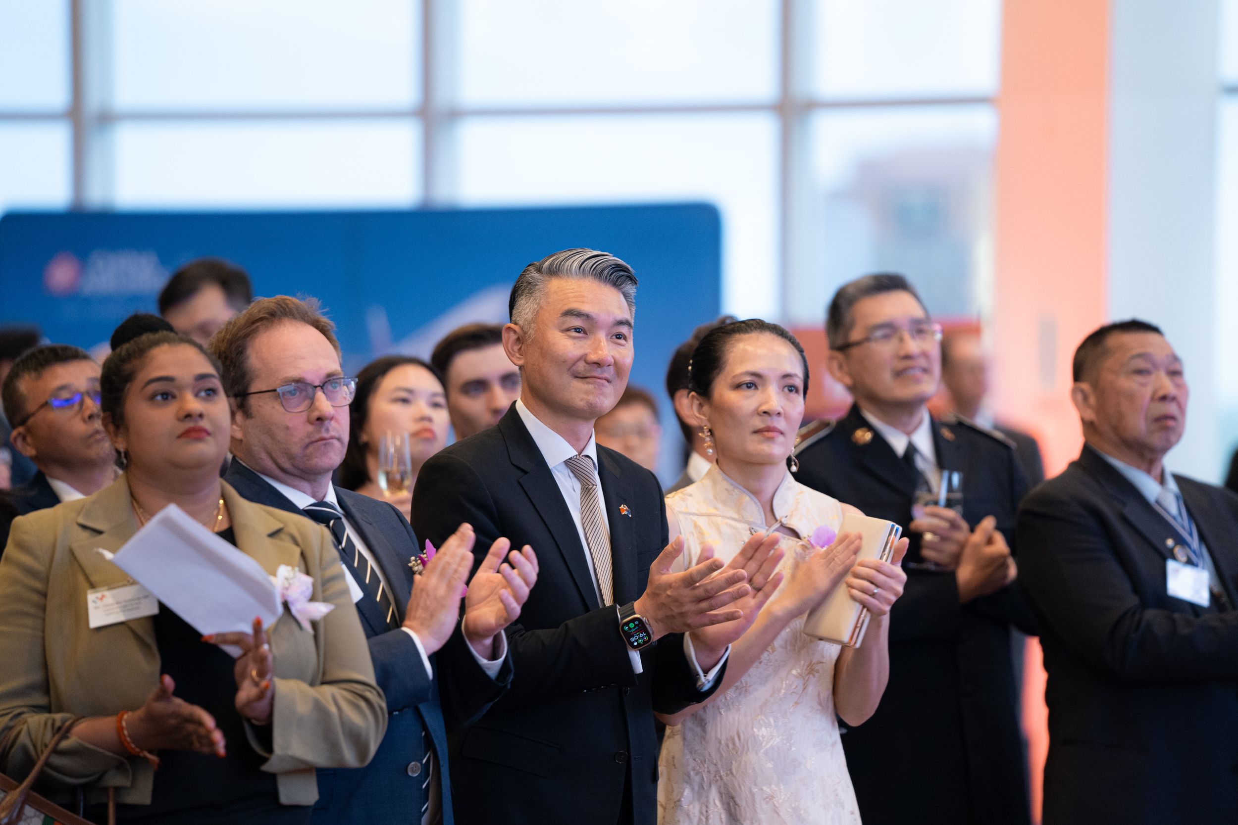 Audience members in business attire applaud during a formal event.