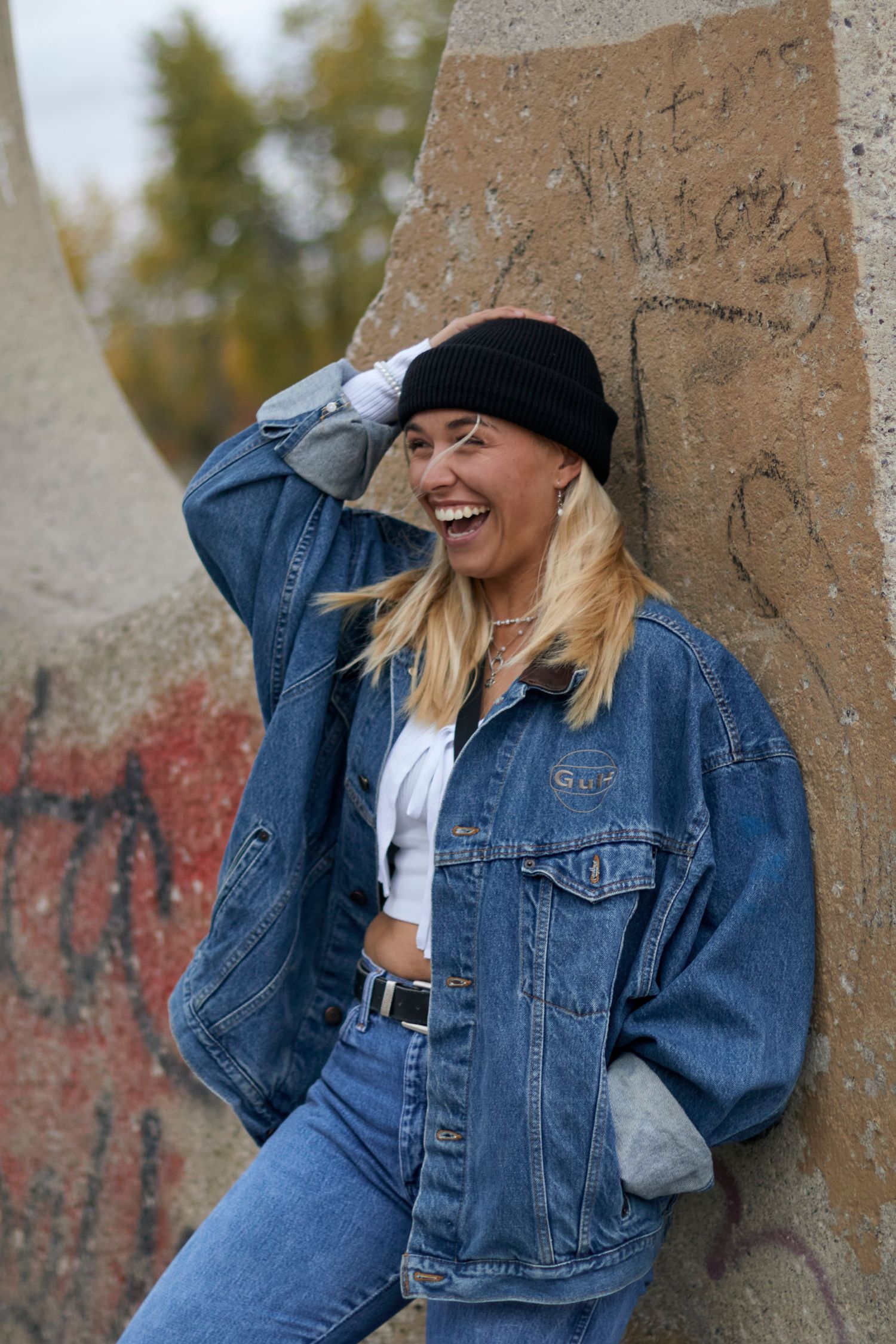 Outdoor photo of a woman holding onto her black hat laughing