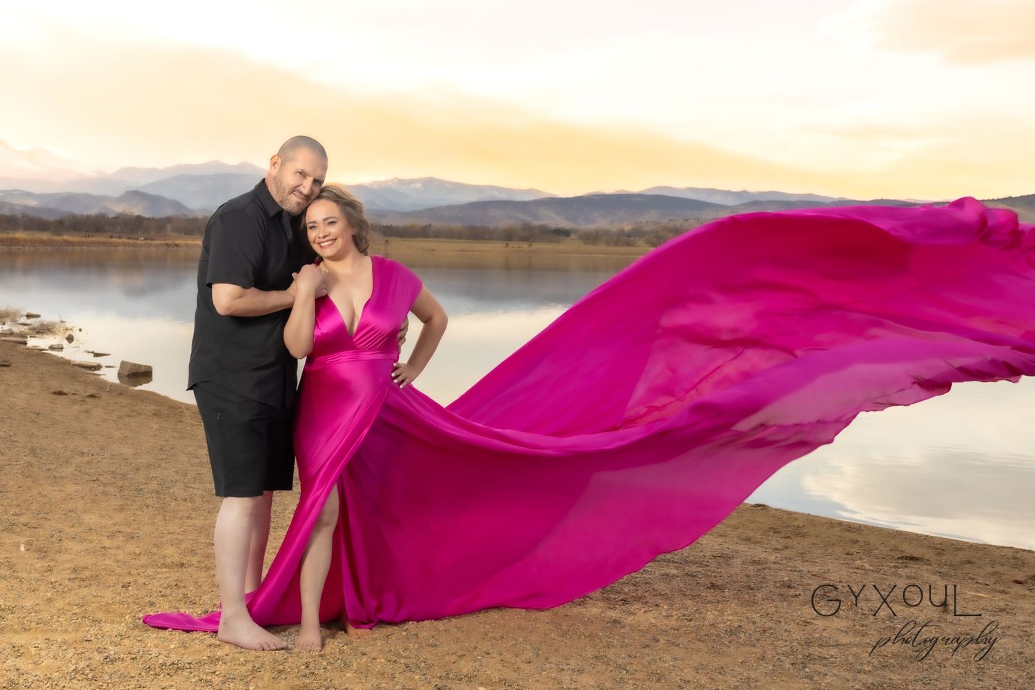 Dramatic photoshoot featuring flowing pink dress against desert landscape at sunset.