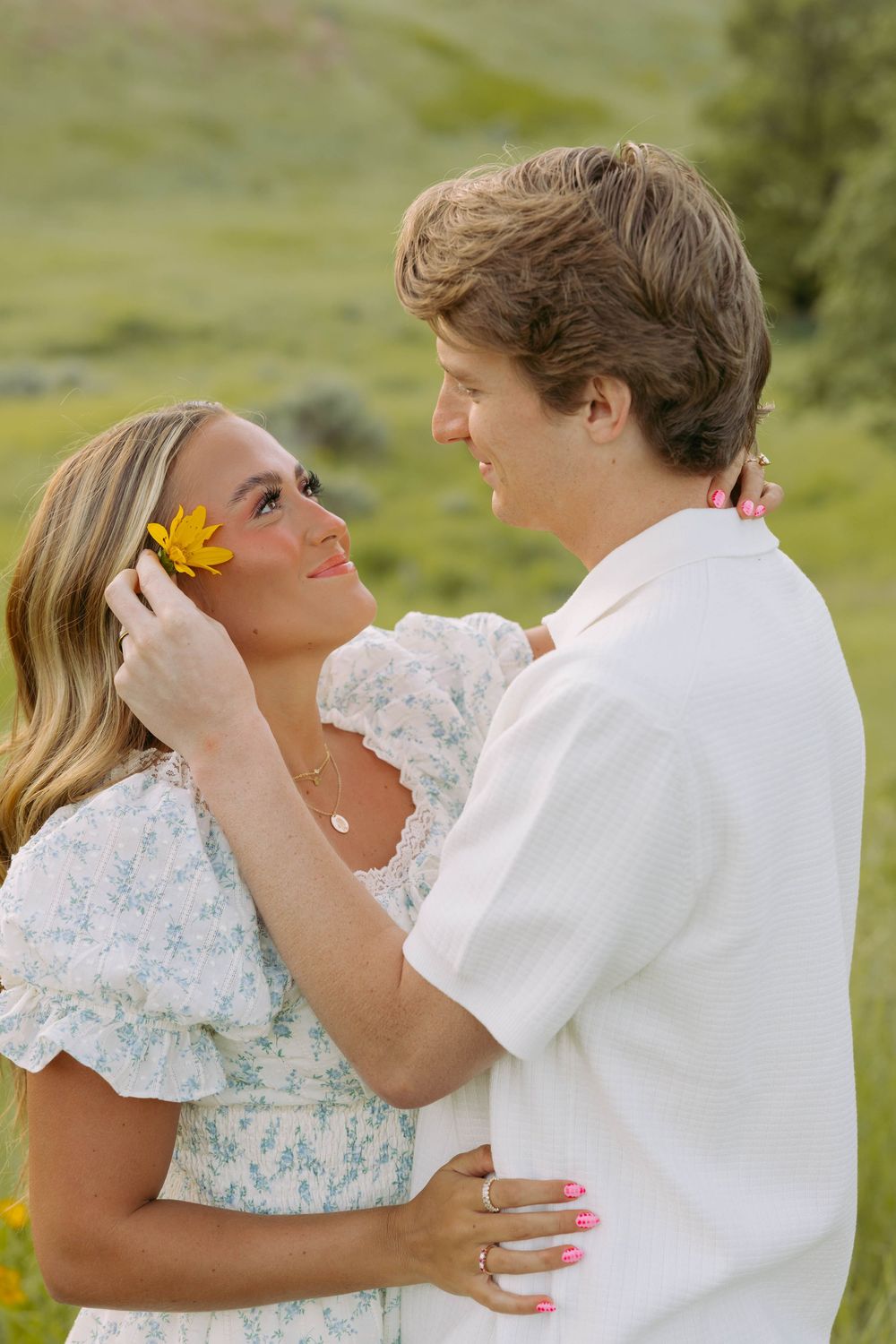 A tender embrace in a sunny meadow with wildflowers as a couple shares an intimate moment together.